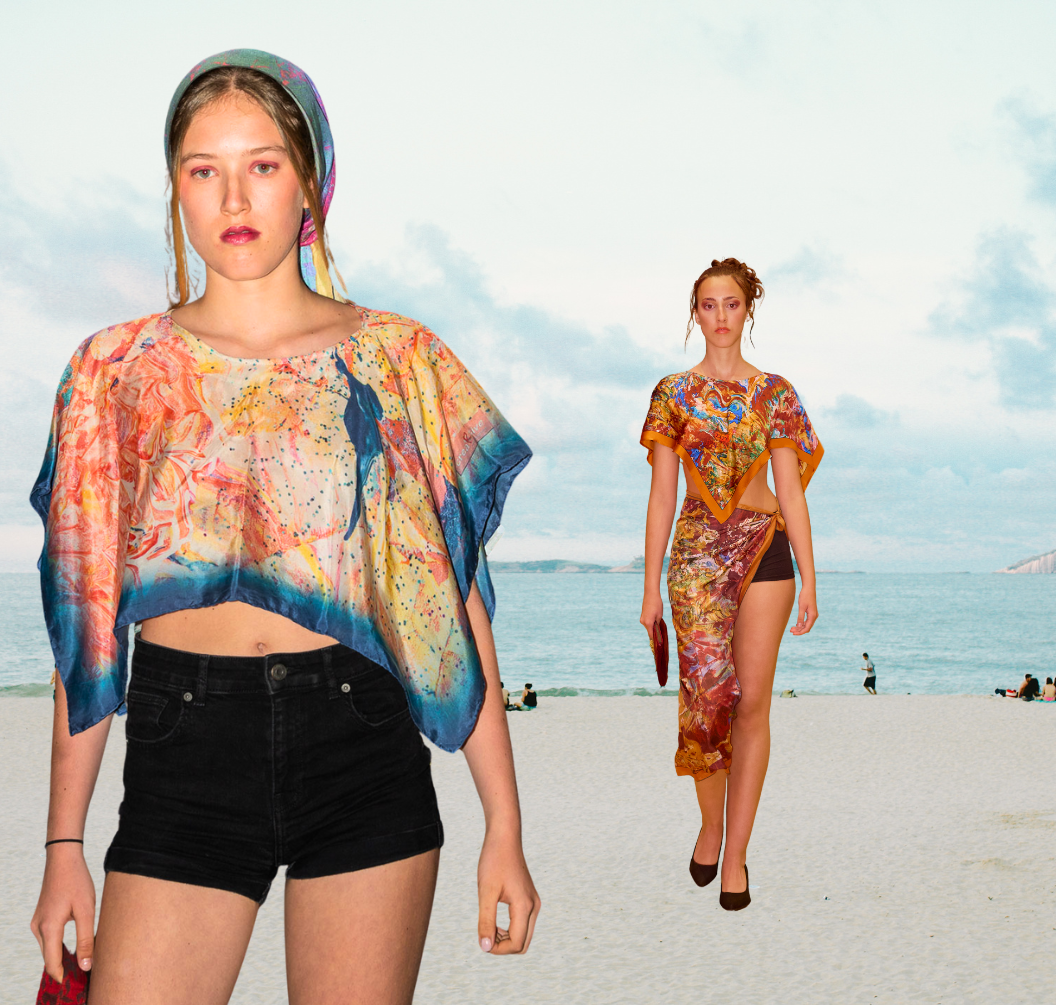 Two women wearing eco-chic painted silk wraps on a beach with ocean and sky in the background.